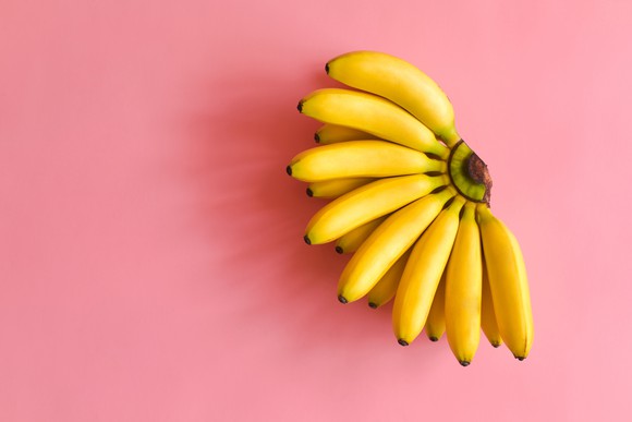 Ripe bunch of bananas on a pink background.