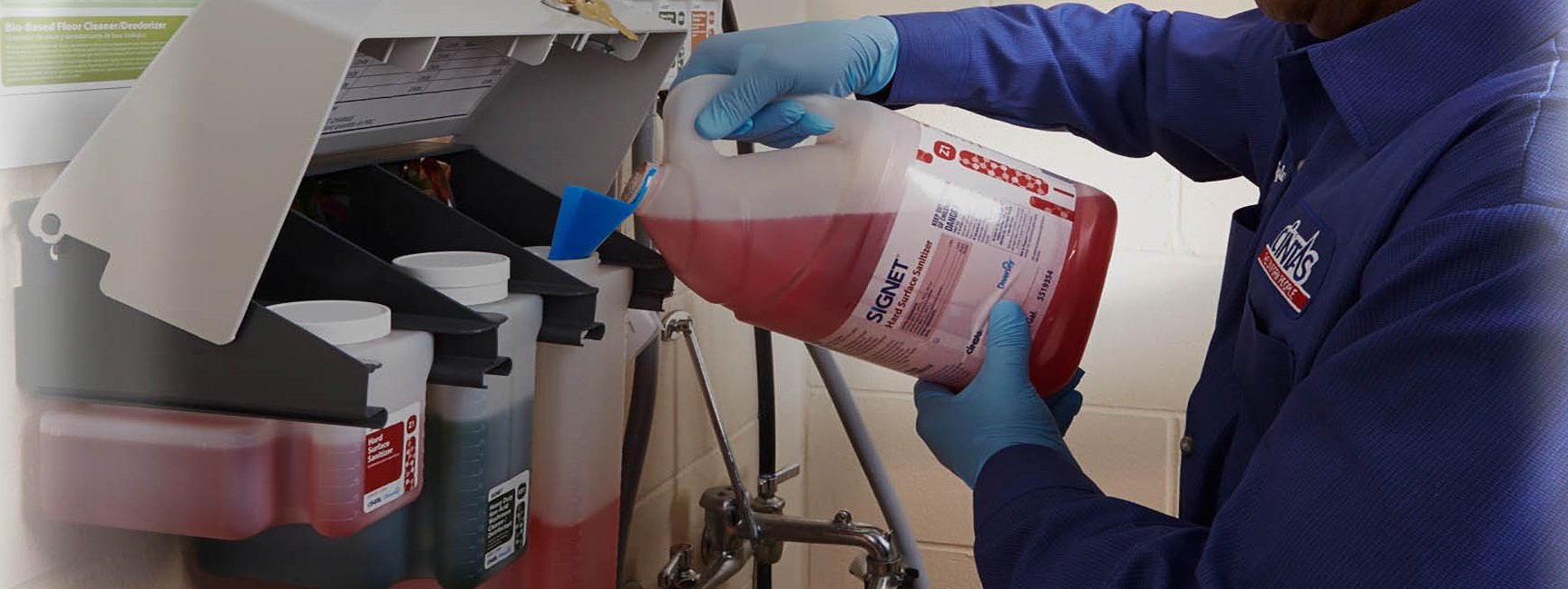 Person pouring red liquid into a dispenser.