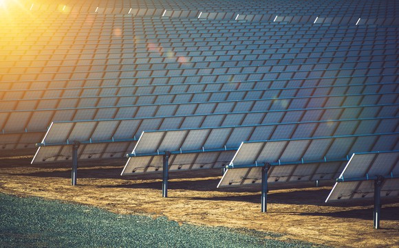 Rows of solar panels with a ray of sunshine in the corner.