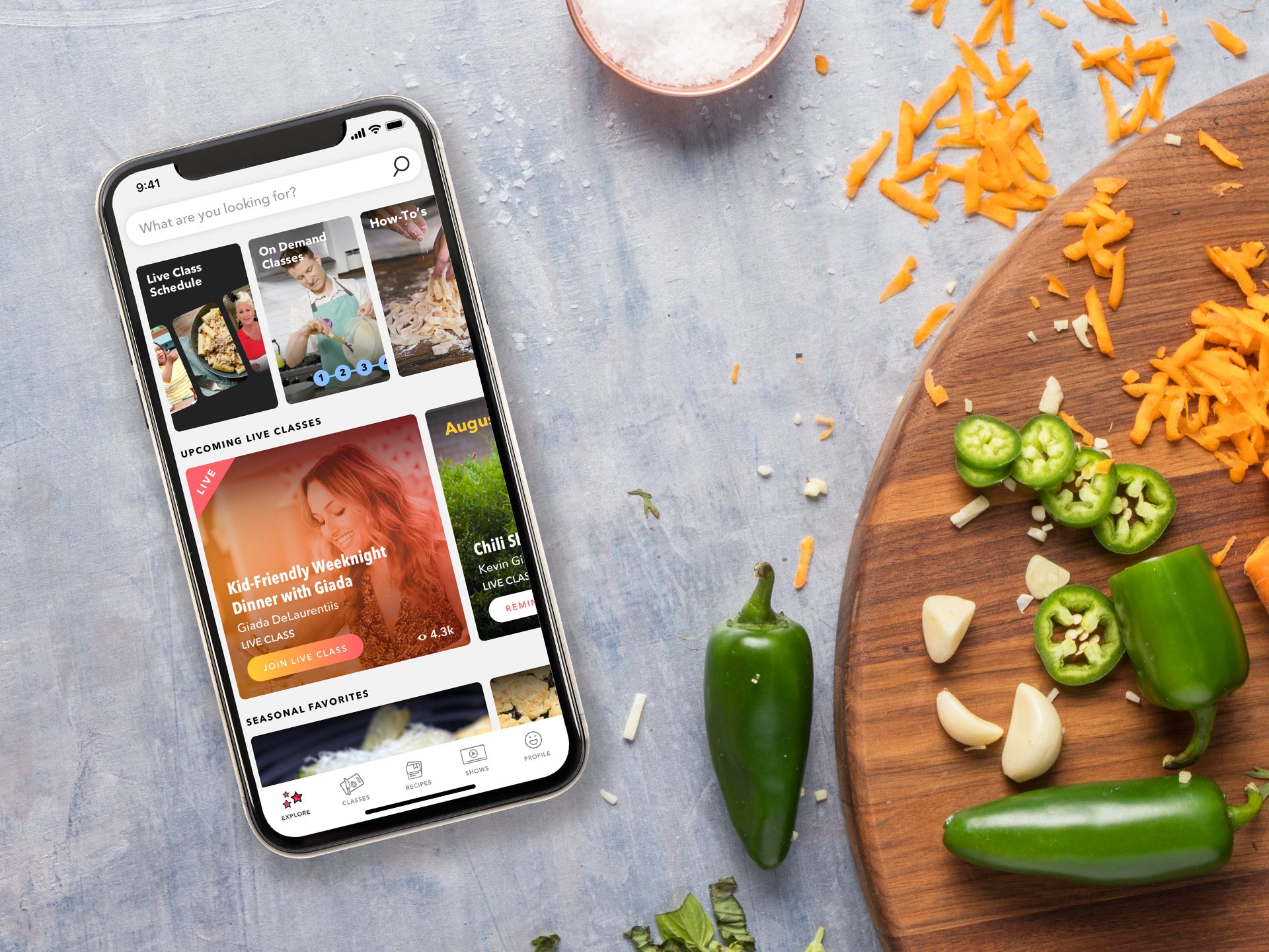 The Food Network Kitchen app on a smartphone next to a chopping board with jalapenos and shredded cheese.