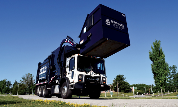 A dump truck lifts a trash container.