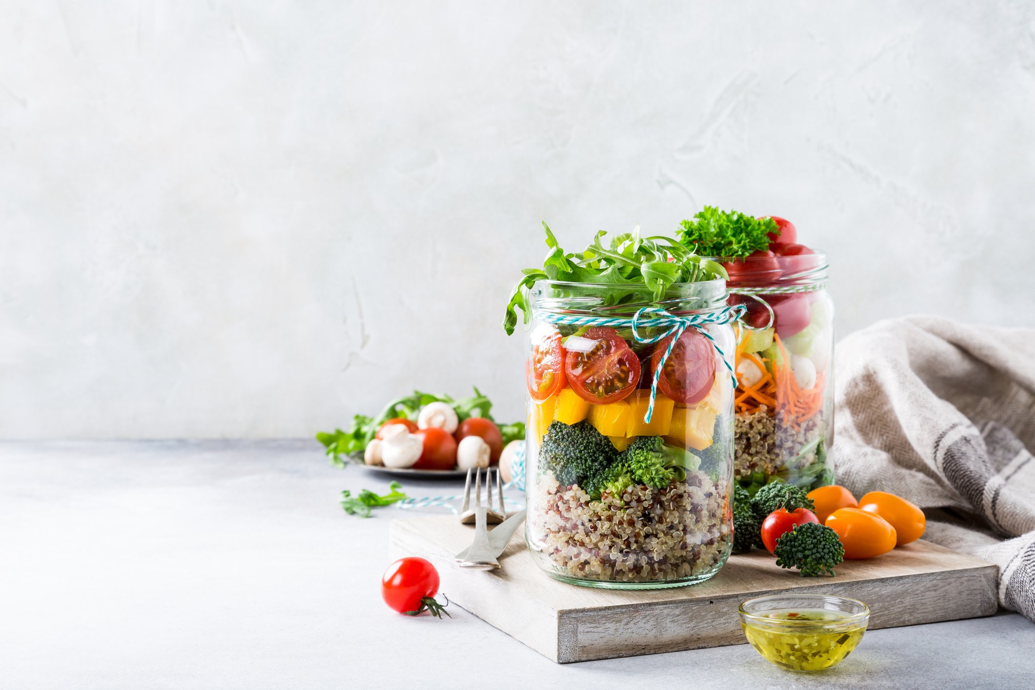 Two mason jars filled with quinoa salad and vegetables.