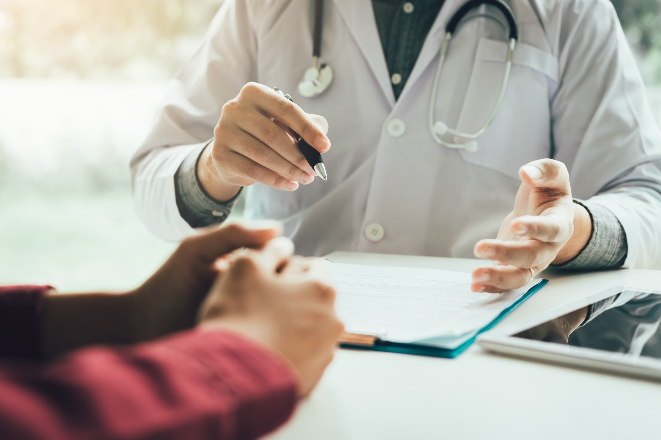 A doctor in a white coat talks with a patient about his chart.