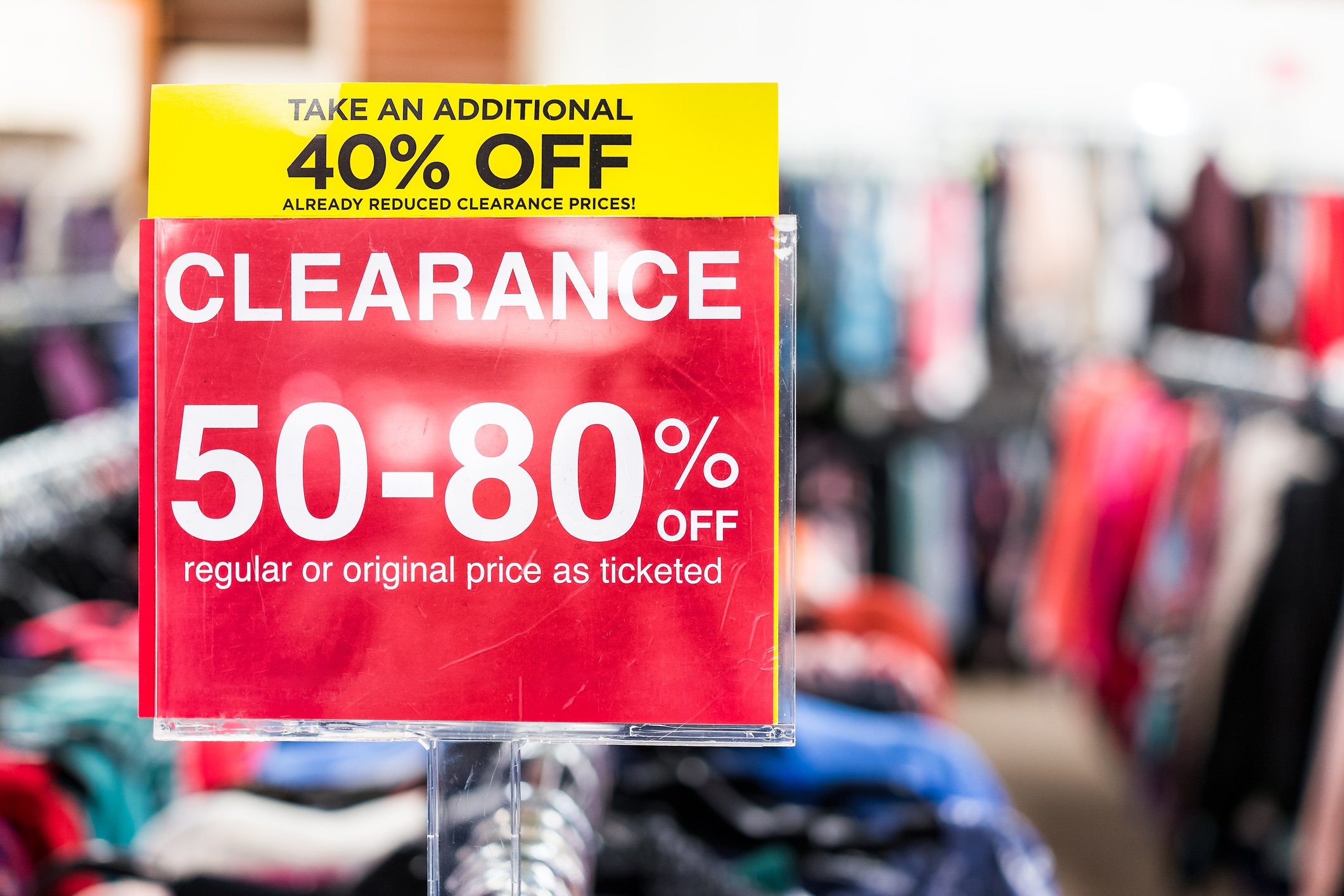 A clearance sign on a rack of clothes.