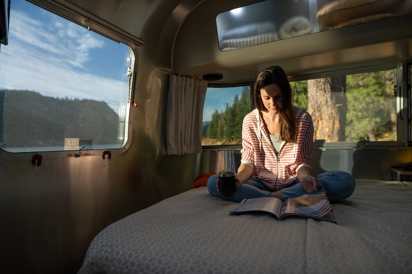 Woman sitting on a bed inside an RV and reading