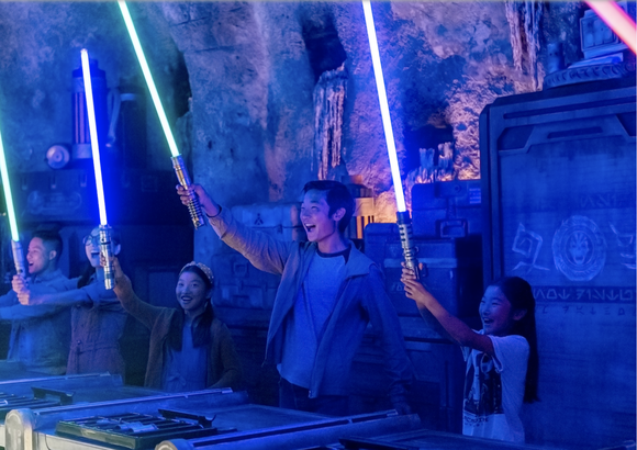 Young kids hold up custom lightsabers at Star Wars: Galaxy's Edge workshop at Disney's Hollywood Studios.