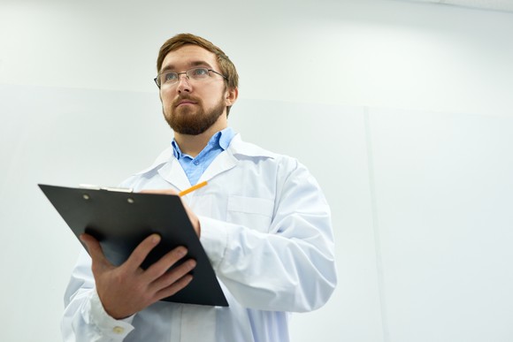 Man in a lab coat with a clipboard.