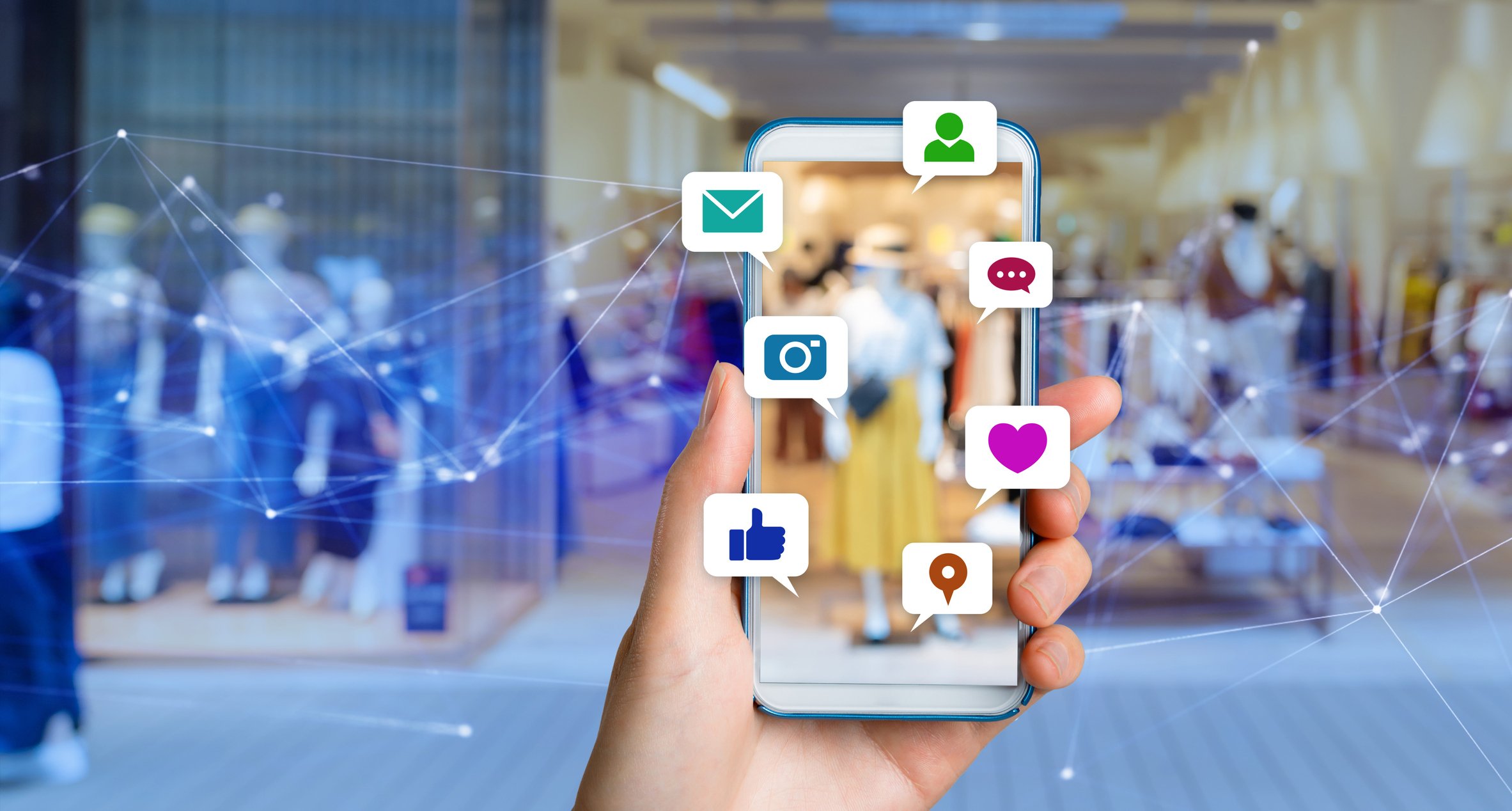 A hand holding up a smartphone showing several social media icons