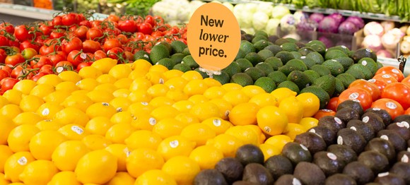 A grocery produce display with a sign saying New lower price.