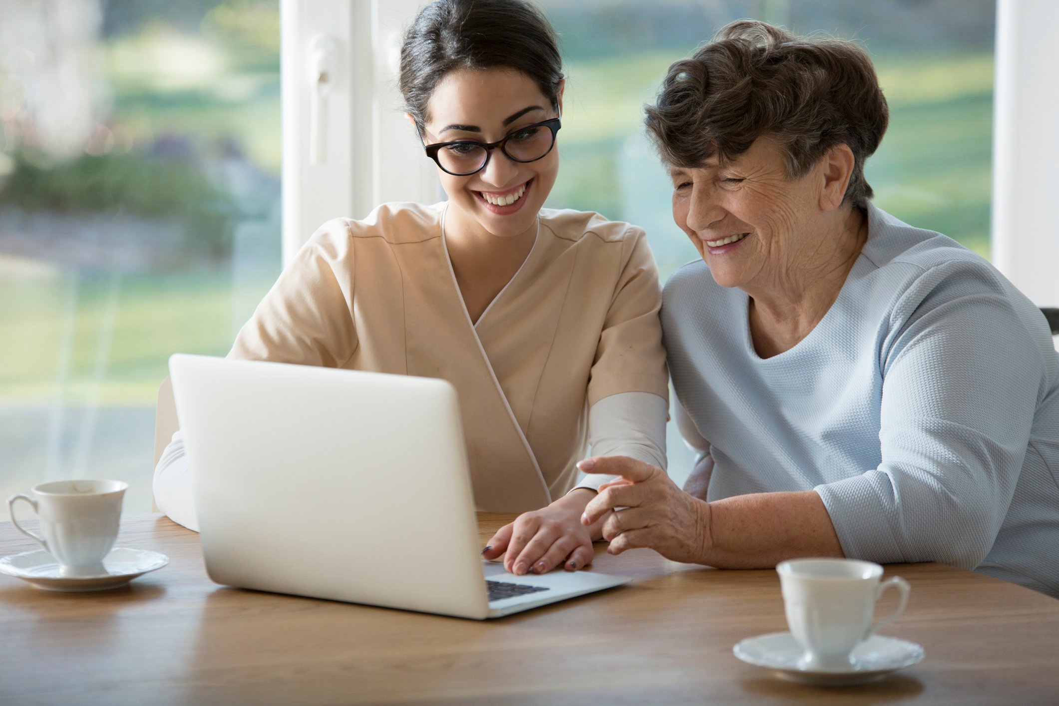 Smiling assistant sitting next to elderly woman