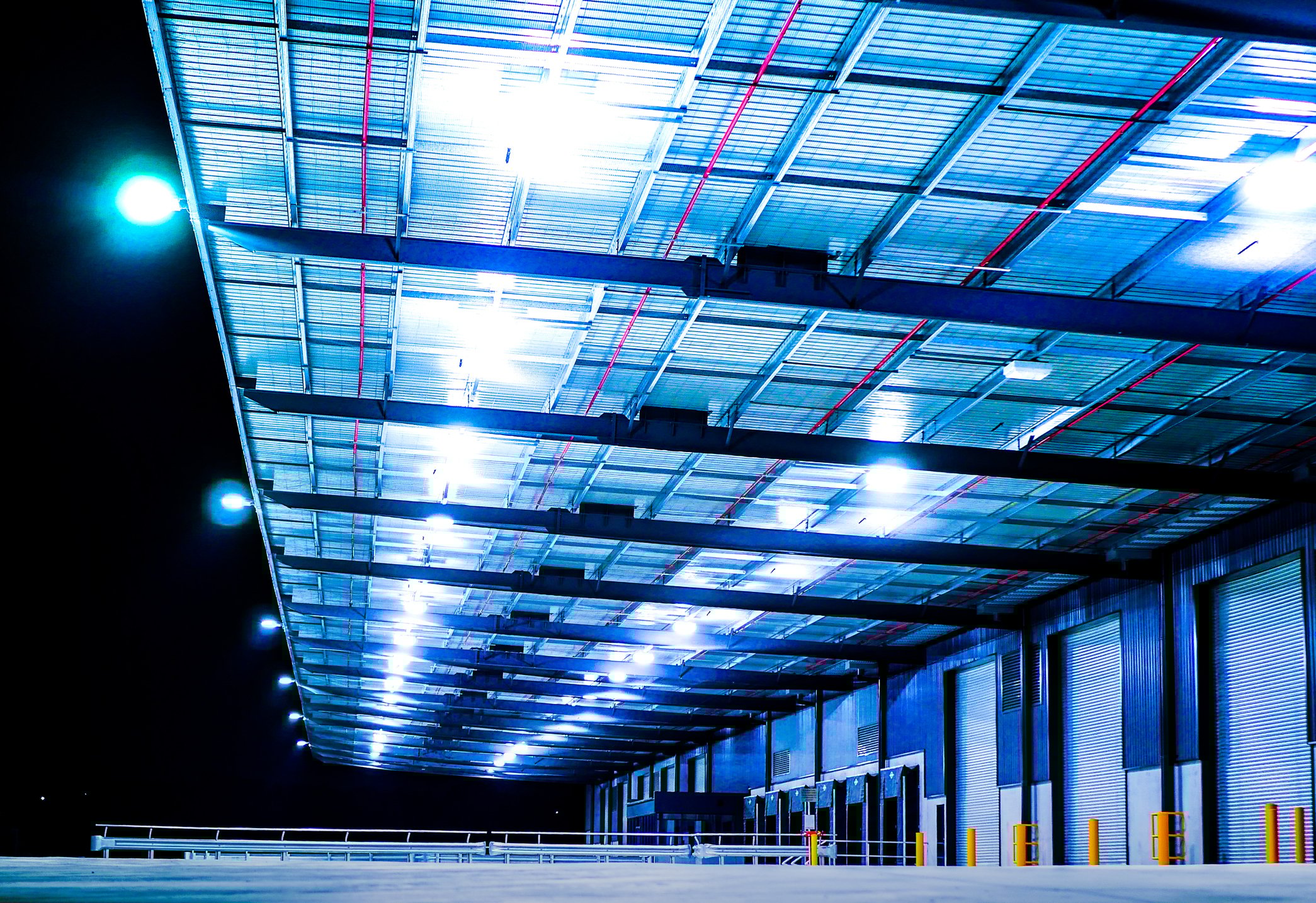 Docking bays of an industrial warehouse lit dramatically at night.