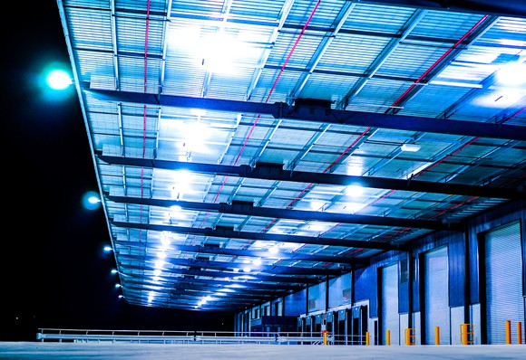 Docking bays of an industrial warehouse lit dramatically at night.