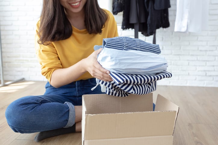 A woman unpacking clothes from a shipping box.