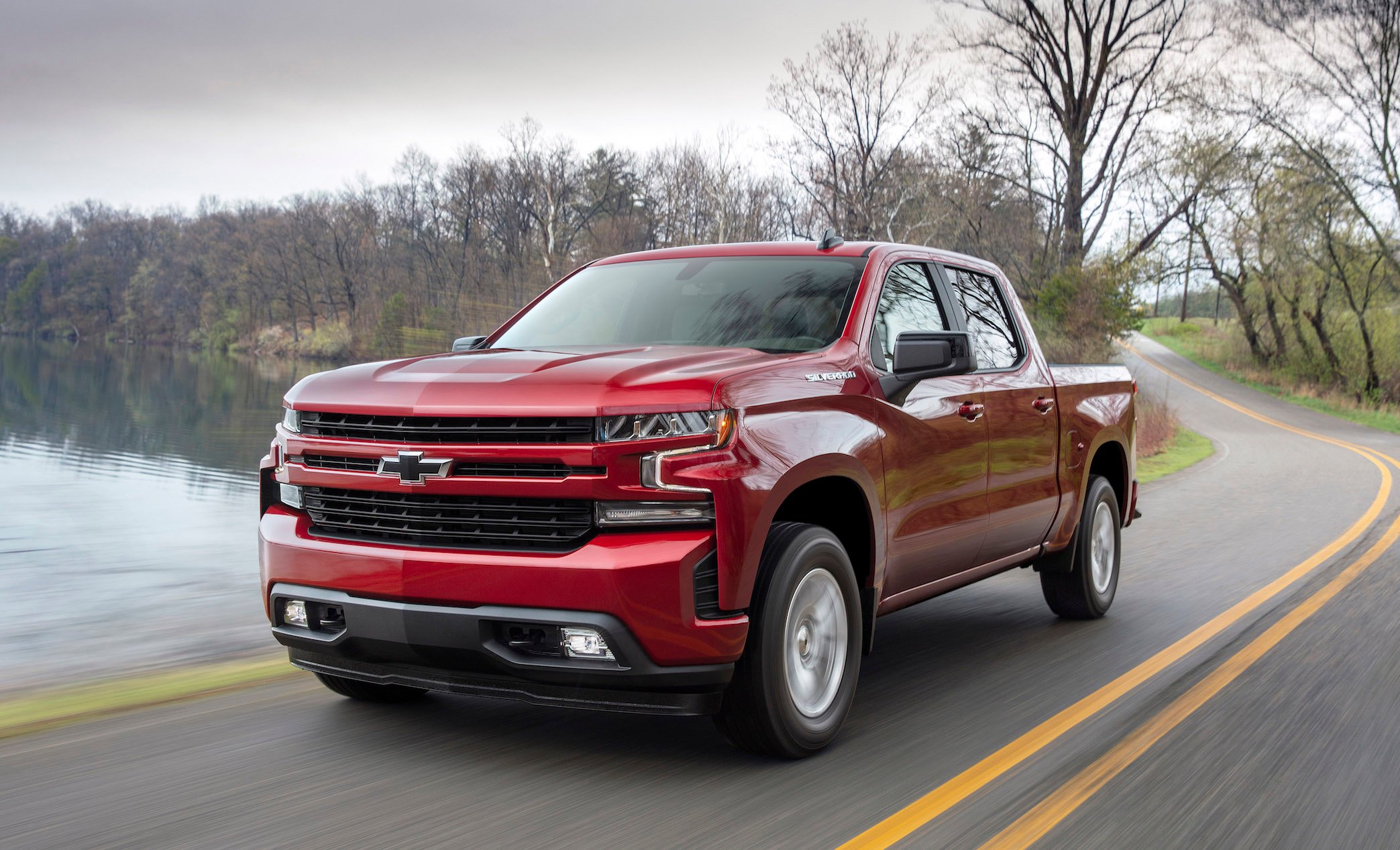A red 2019 Chevrolet Silverado 1500, a light-duty full-size pickup truck, on a road near a lake.