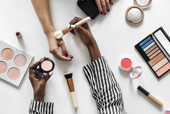 Two women testing cosmetics on a table