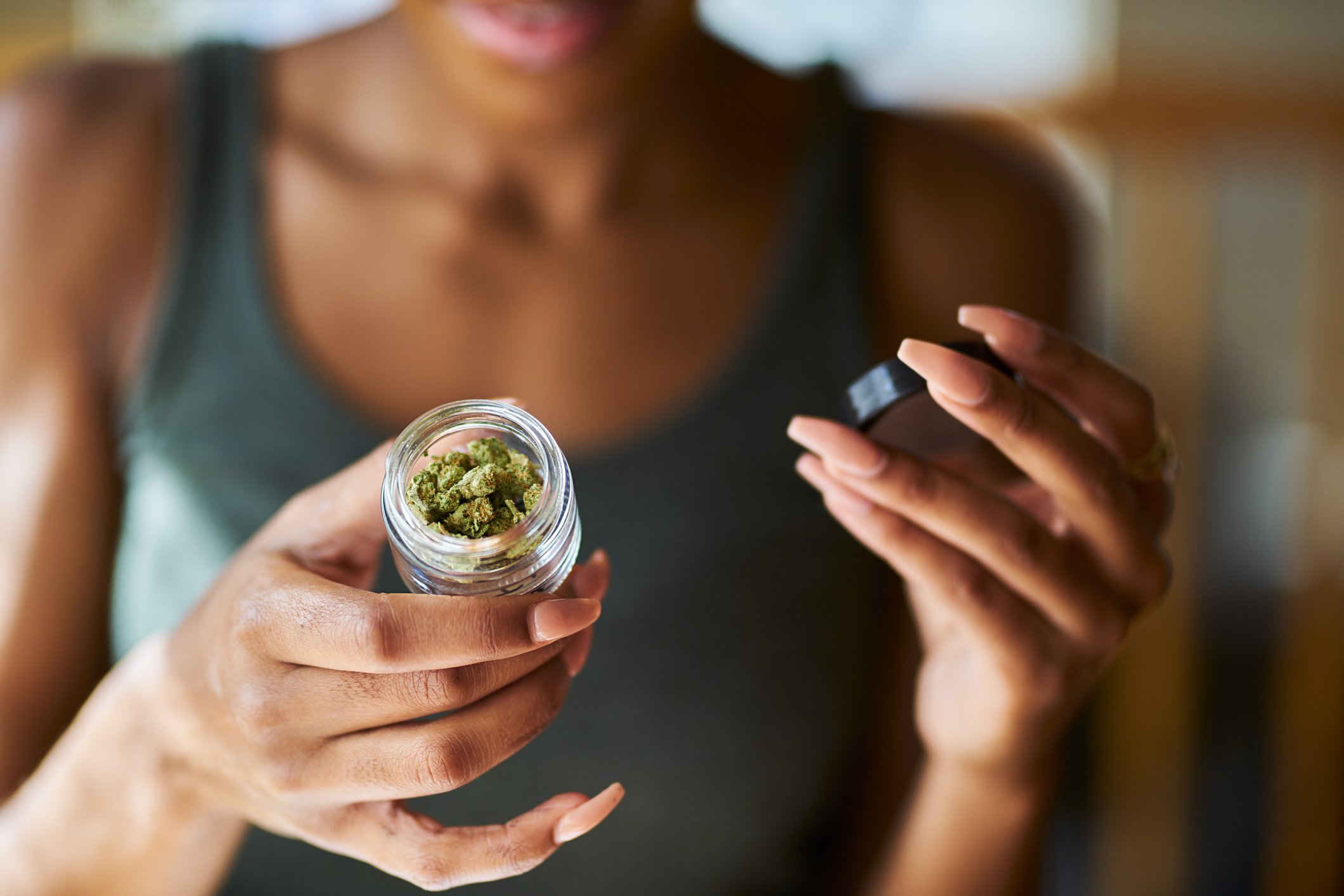 A woman holds a jar of cannabis in her hand. 