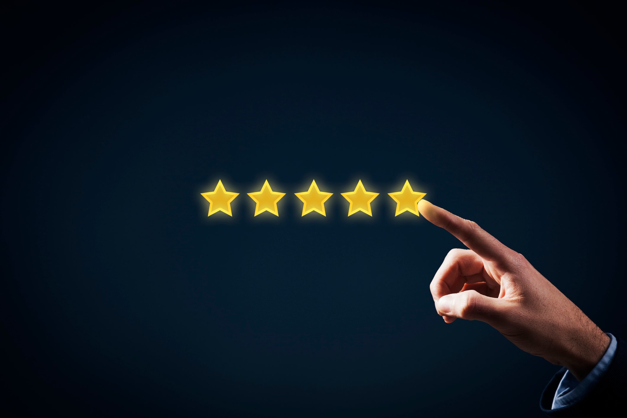 A businessman pointing to five yellow stars in a row.