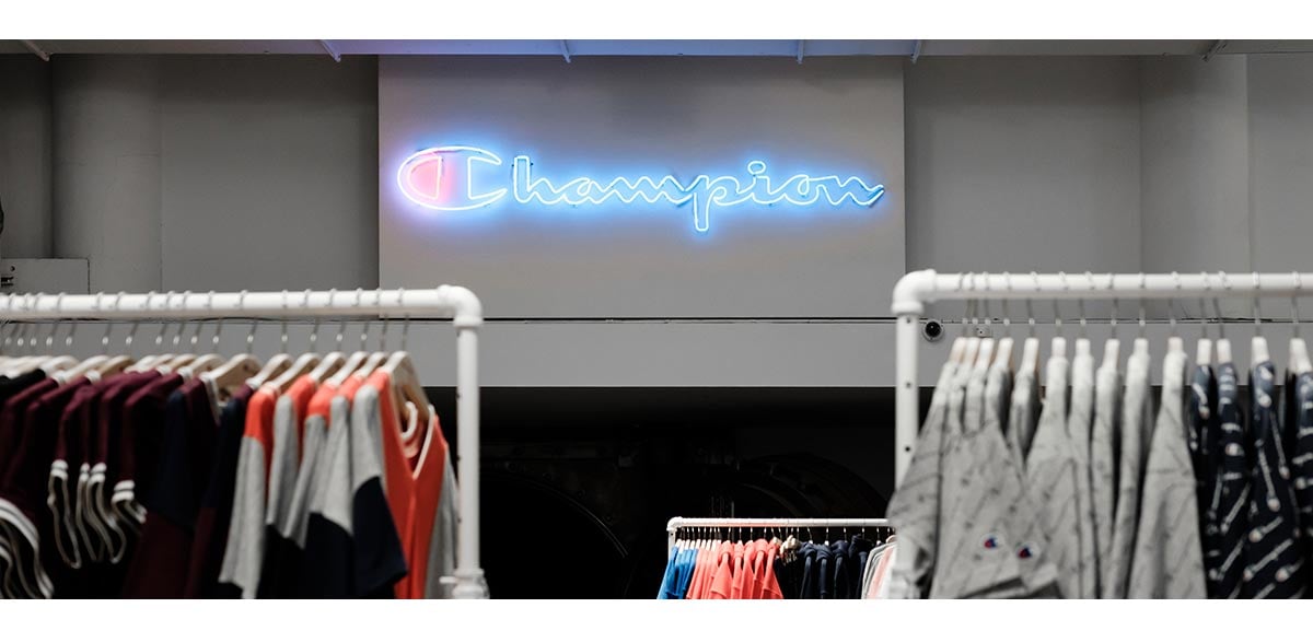 A store with the Champion logo in neon blue and red displayed on a wall.