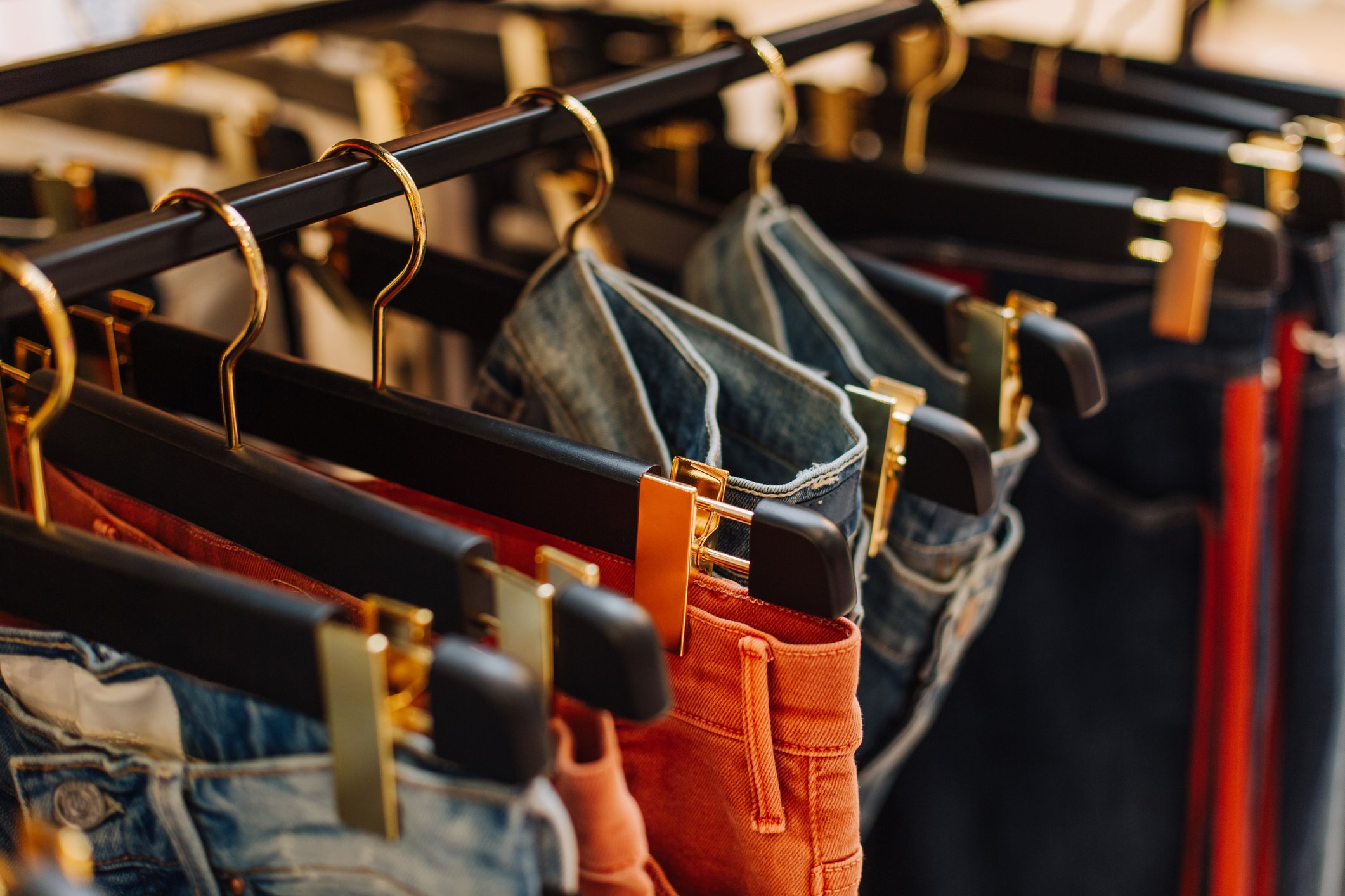 Colorful assorted blue jeans on a rack in a boutique clothing store.