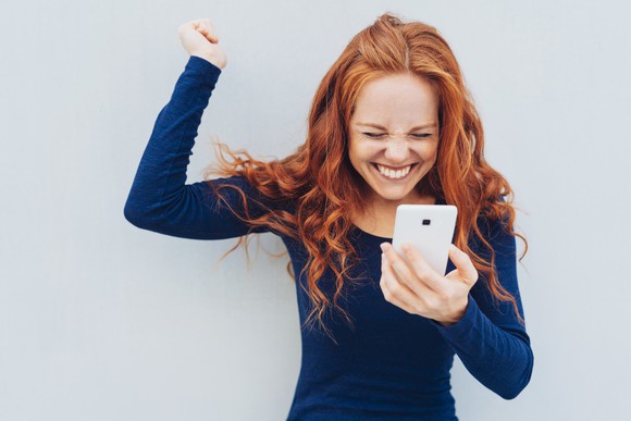 A young woman is excited about something on her smartphone.