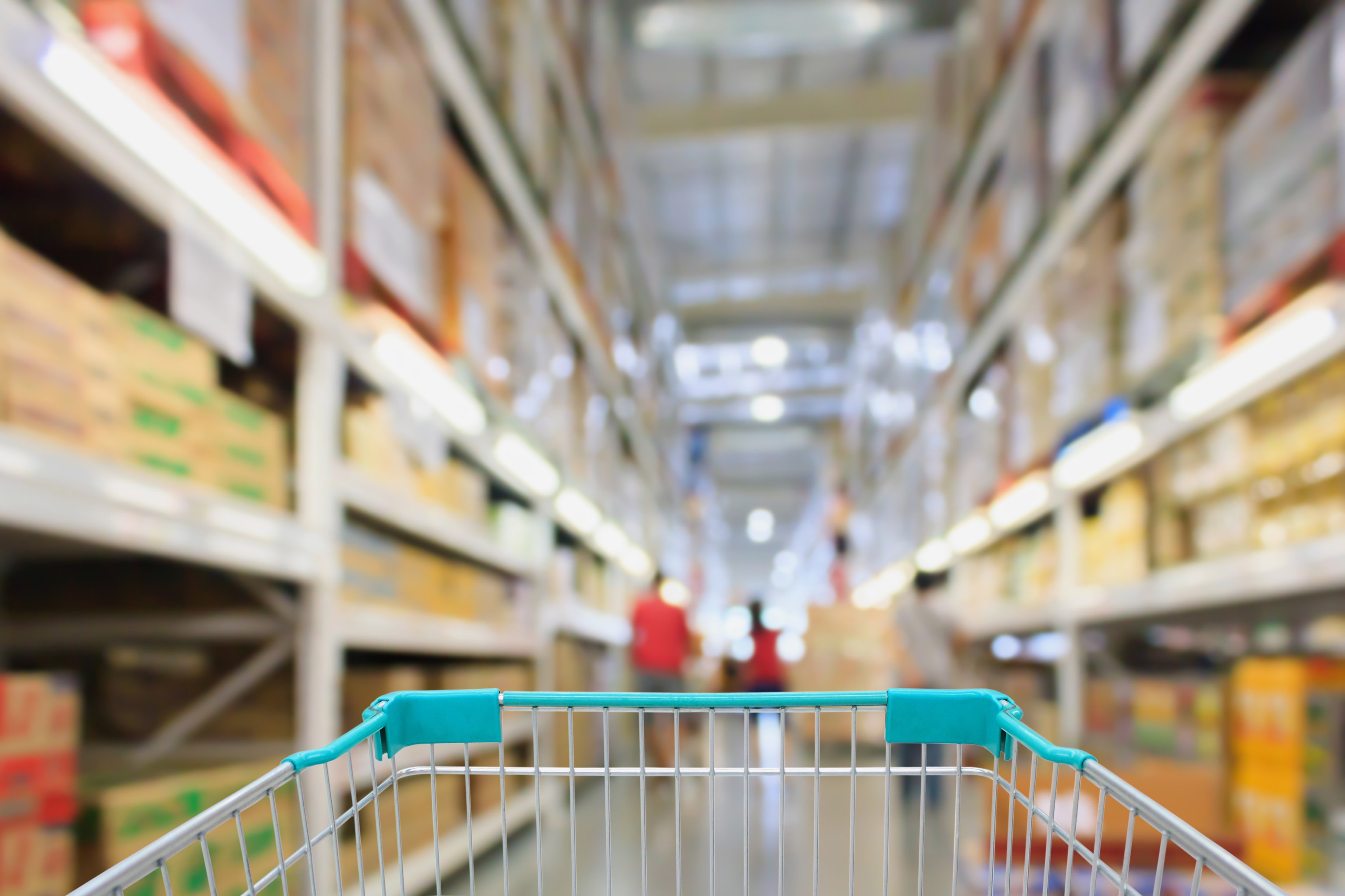 A grocery cart in a shopping aisle at at wholesale store.