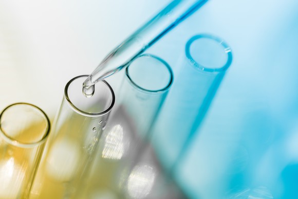 An eyedropper drips clear liquid into a test tube.