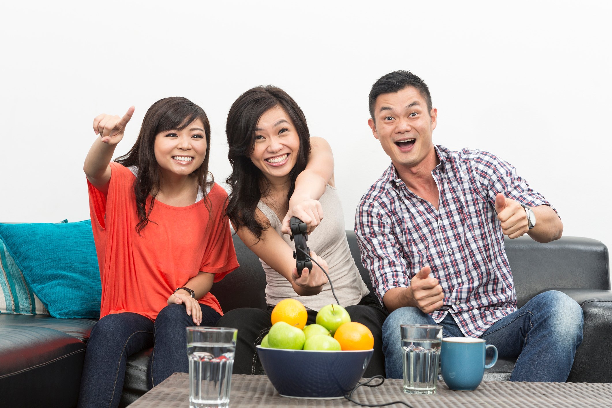 Two Chinese women and a man playing video games on a couch