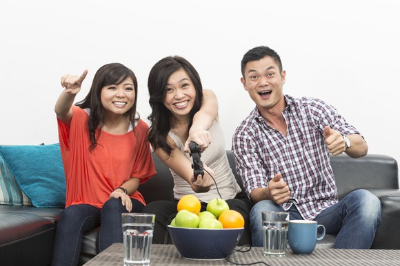 Two Chinese women and a man playing video games on a couch