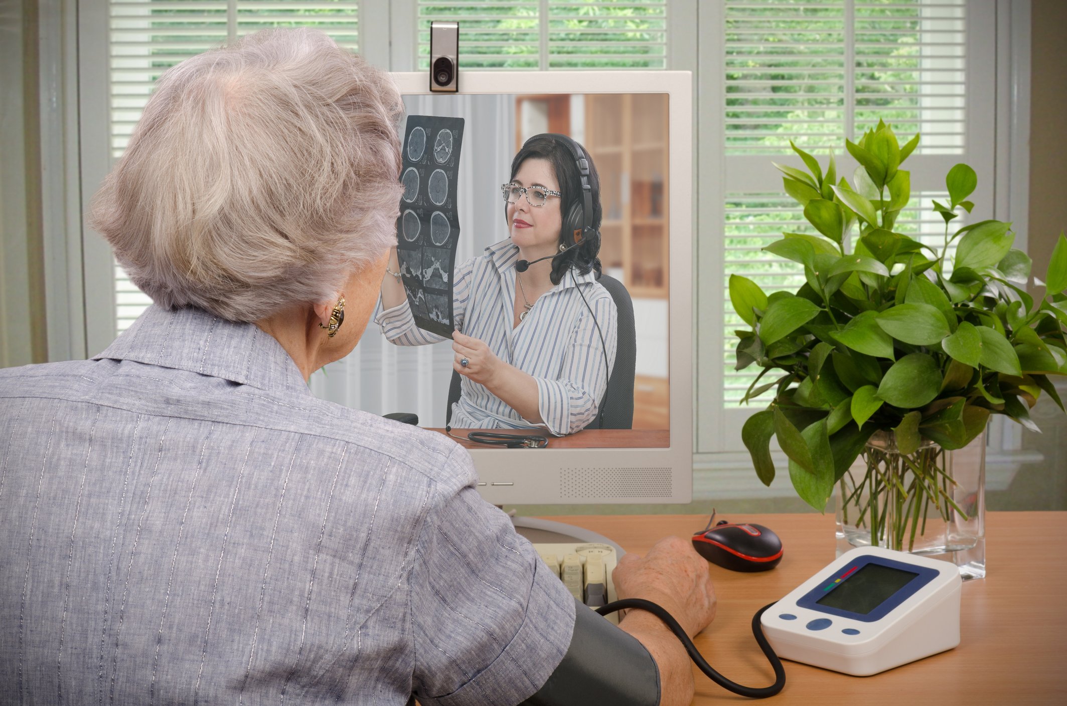 A person with a blood pressure cuff on their arm having a videoconference with a doctor.