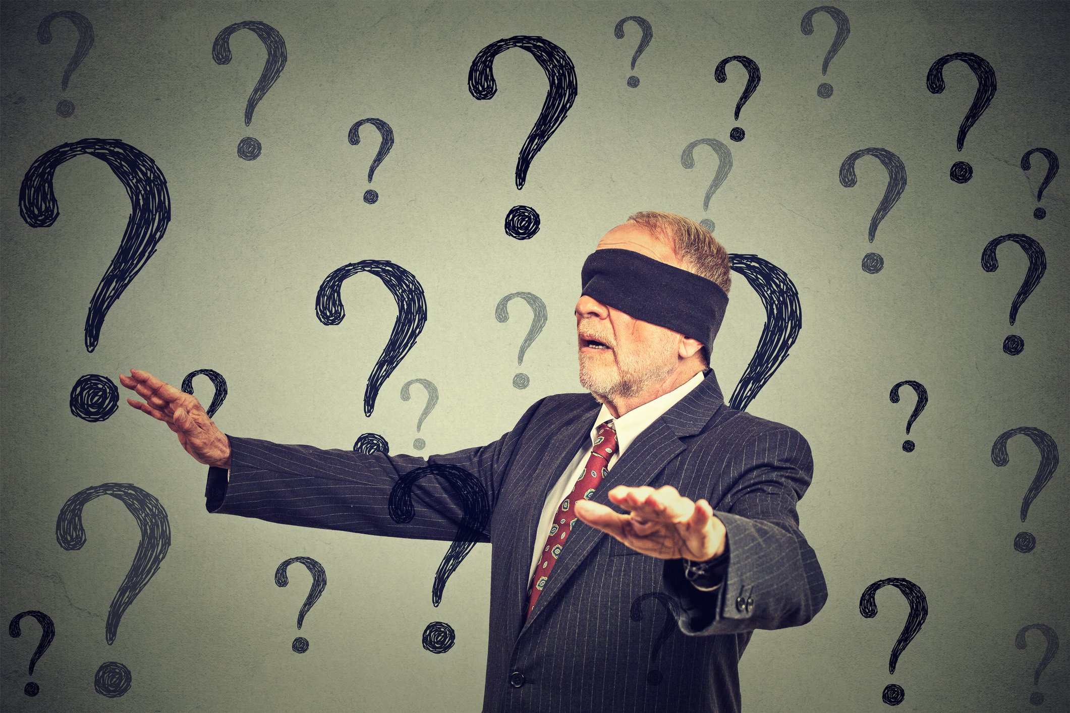 A blindfolded older businessman walks with hands outstretched, surrounded by question marks.