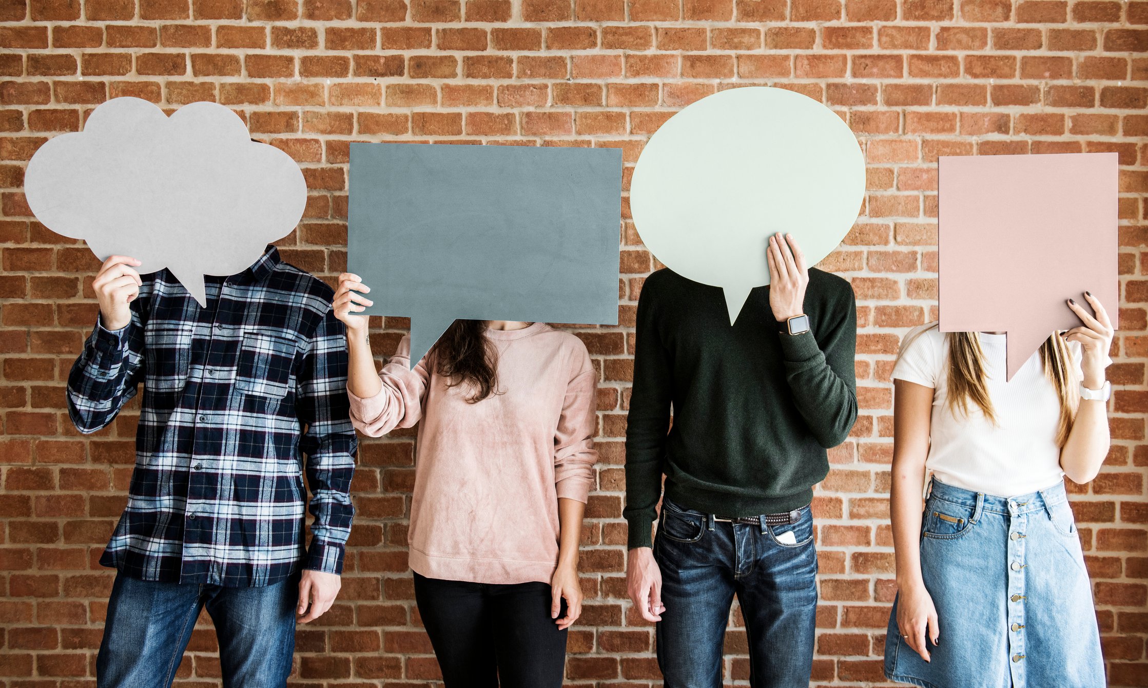 Young adults holding cardboard cutouts of speech bubbles.