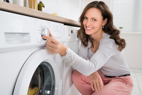A woman uses a laundry machine.