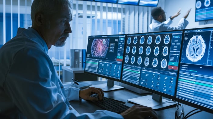 MRI technician looking at three computer monitors