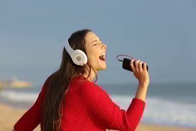 woman singing into phone on beach