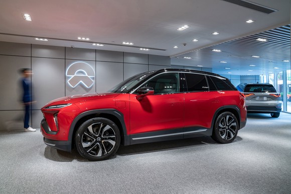 Red SUV in a showroom with the NIO logo on the wall.