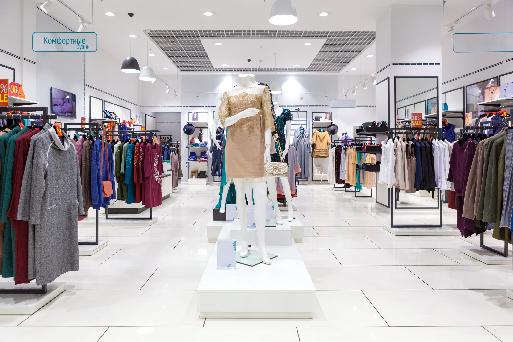 Women's apparel hanging on racks in an empty retail store.