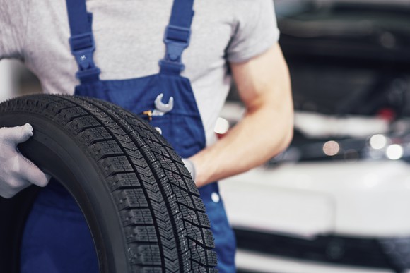 A mechanic holding a spare tire.
