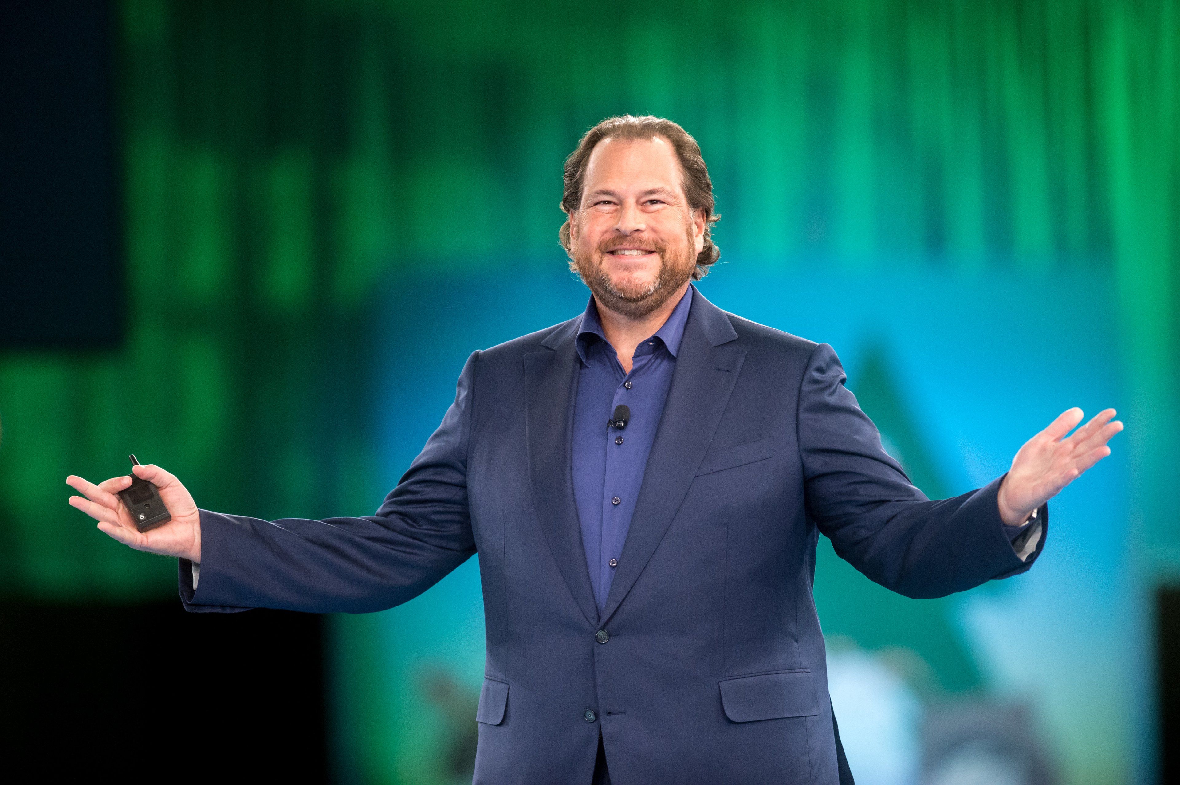 Salesforce co-CEO Marc Benioff with arms extended against blurry green and blue background