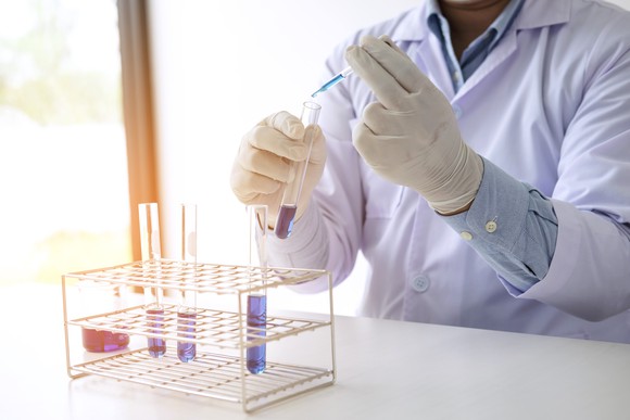 Scientist holding a test tube containing a blue liquid.