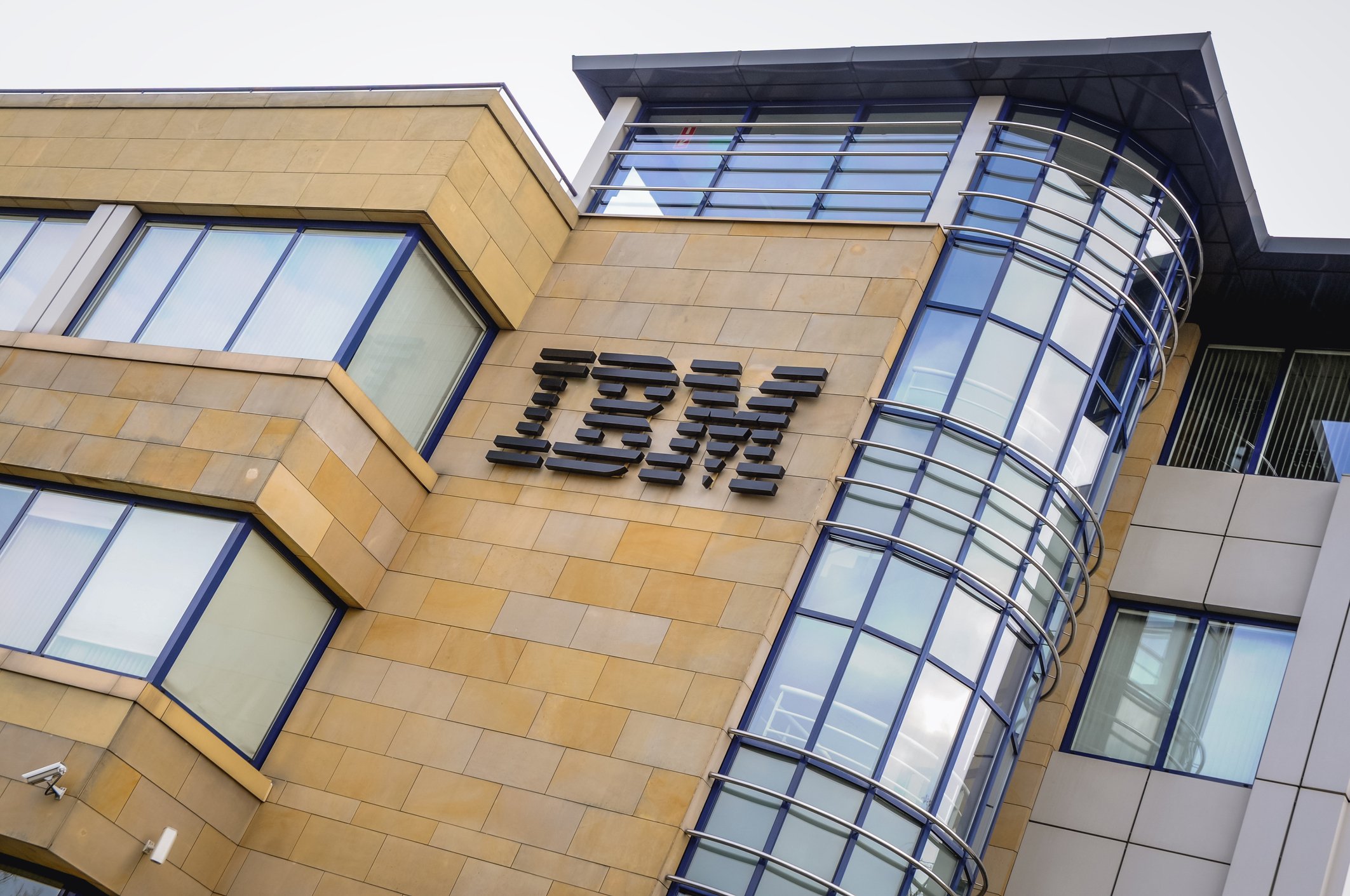 A diagonal angle picture of the IBM logo on a tan brick-and-glass building.