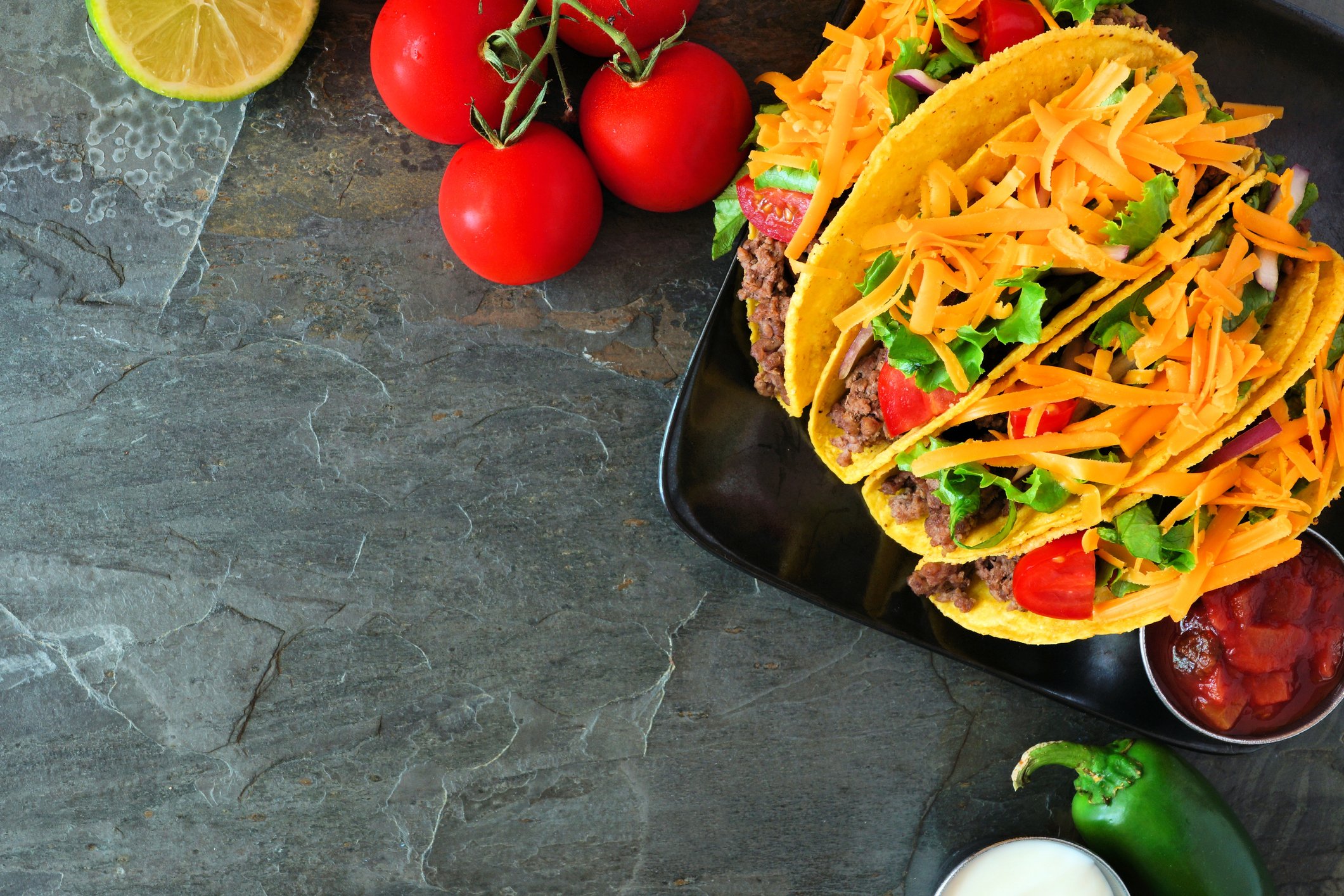 Tacos on a serving board on a gray counter.