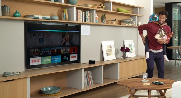 Man and son playing while looking at television displaying Fire TV Cube interface