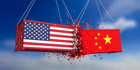 Two shipping containers, one painted with the American flag, the other with the Chinese flag, hanging from unseen cranes and colliding violently.