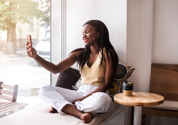 A young woman watches a video on her phone.