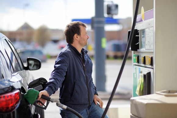 A man pumping gasoline into a car.