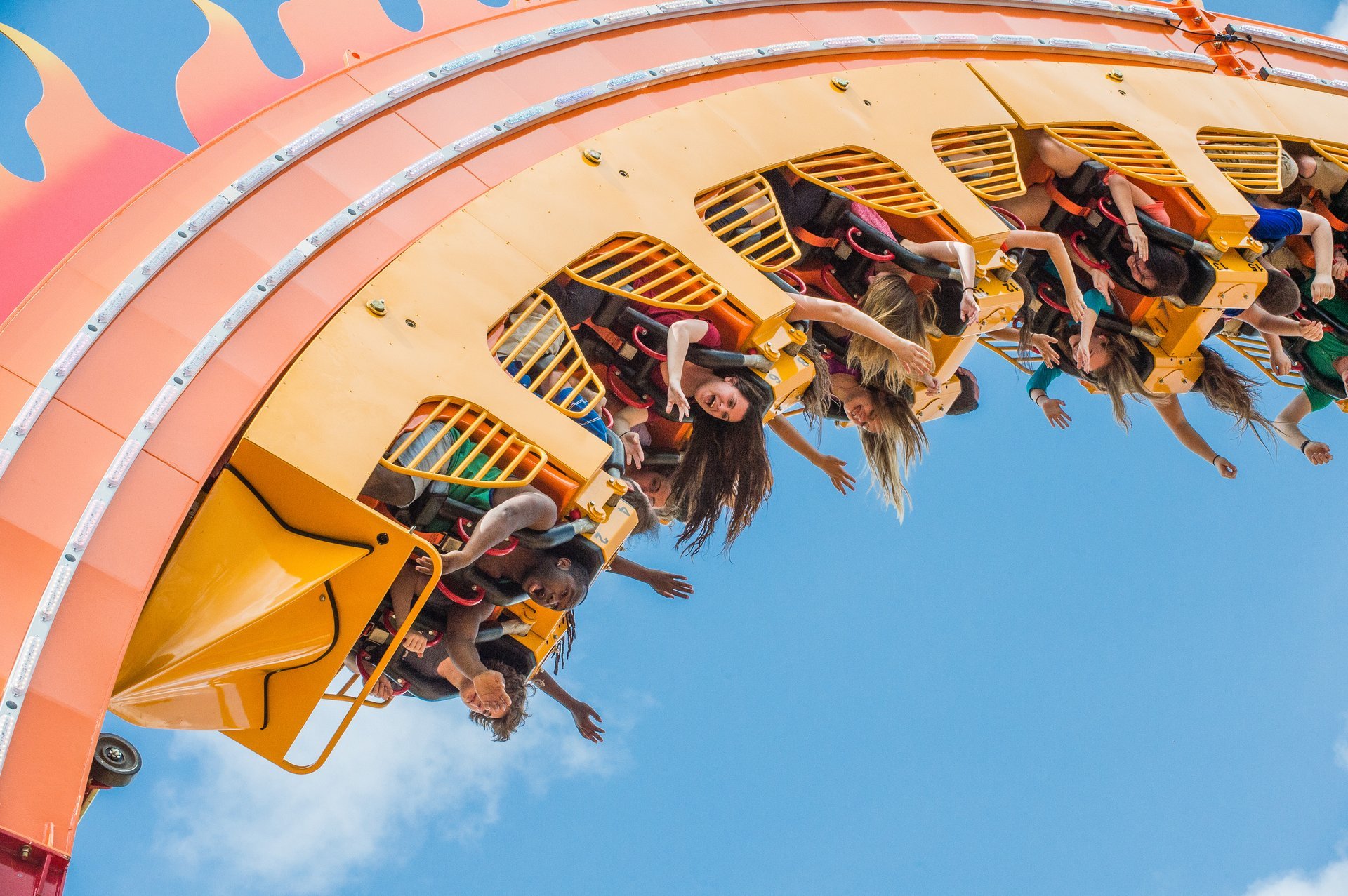 An upside-down roller coaster with riders holding out their hands