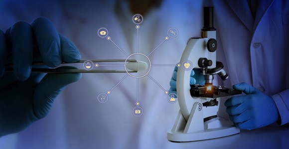 Scientist holding pill in tweezers