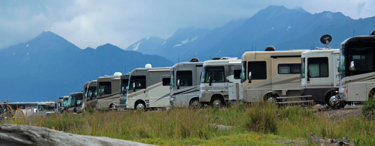 A row of Winnebagos against a mountain background.