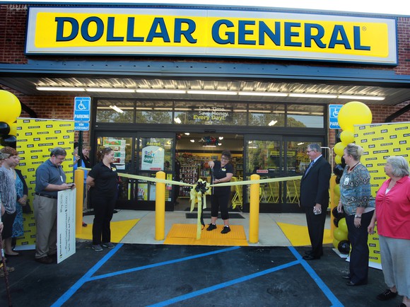 Dollar General store with woman cutting a yellow ribbon as several people watch.
