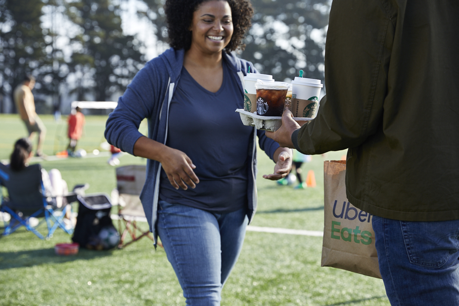 A soccer mom receives a Starbucks delivery at her children's game. 